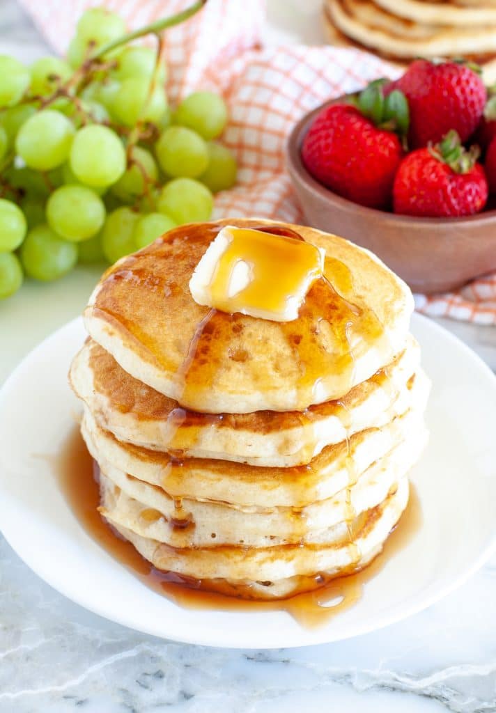 Plate with a stack of pancakes and syrup.