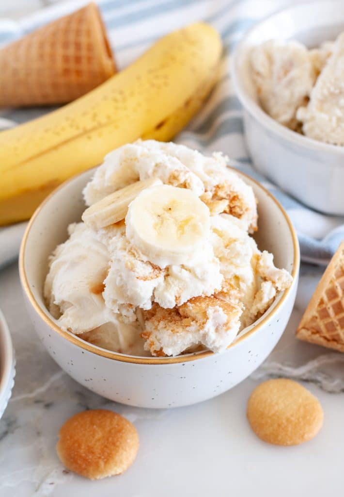 Bowl of ice cream topped with bananas. 