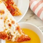 Pizza slice being dipped in melted butter.