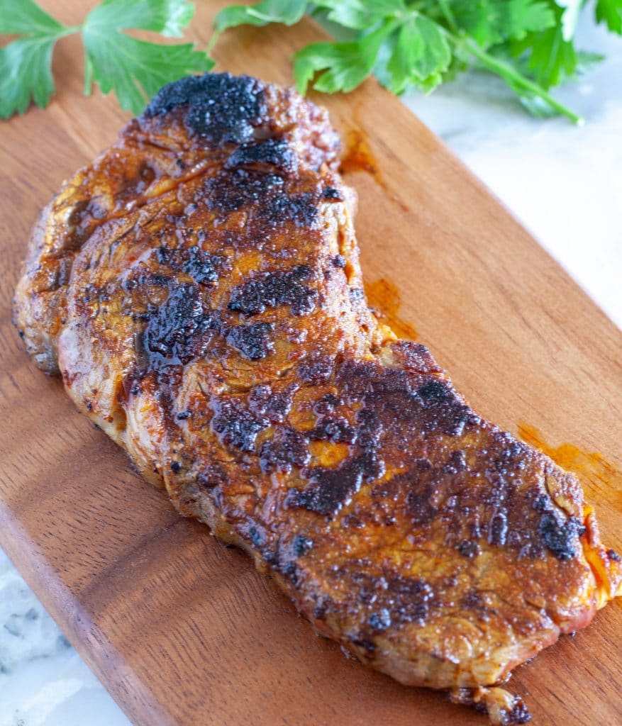 Cooked steak on cutting board.