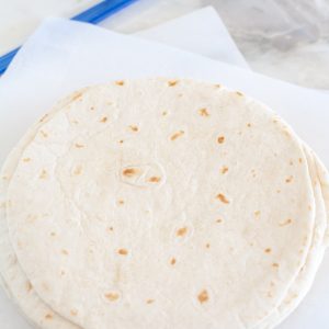 Stack of tortillas on parchment paper.