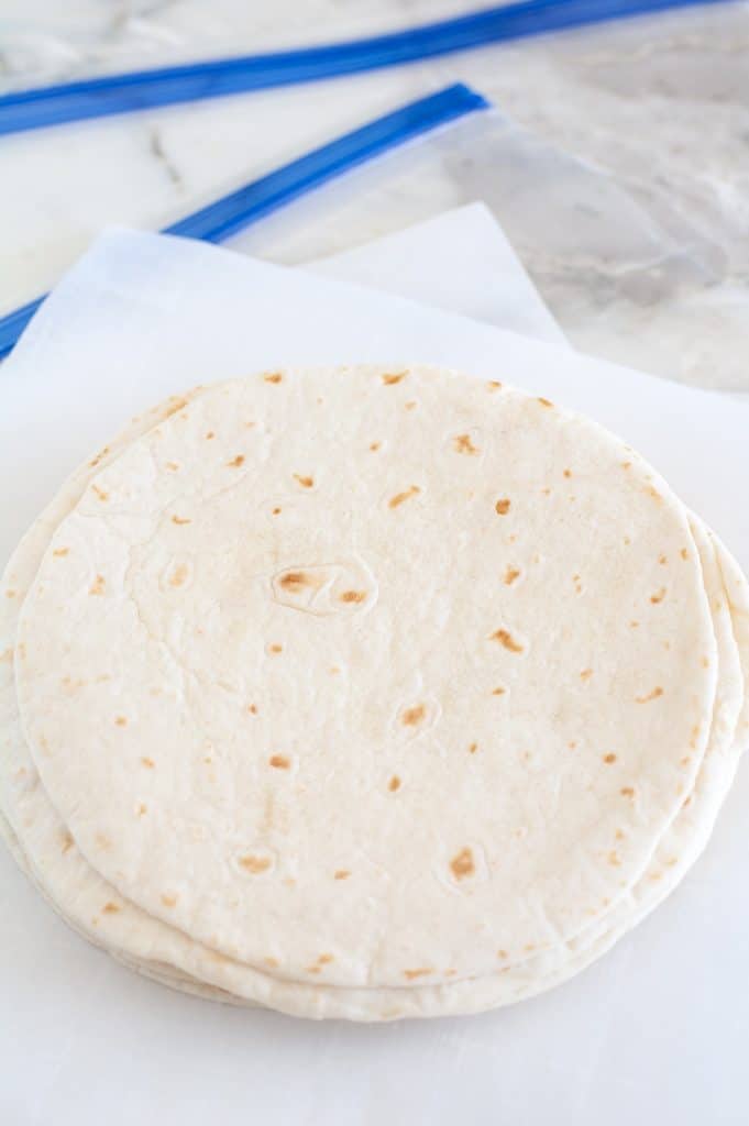 Stack of tortillas on parchment paper. 