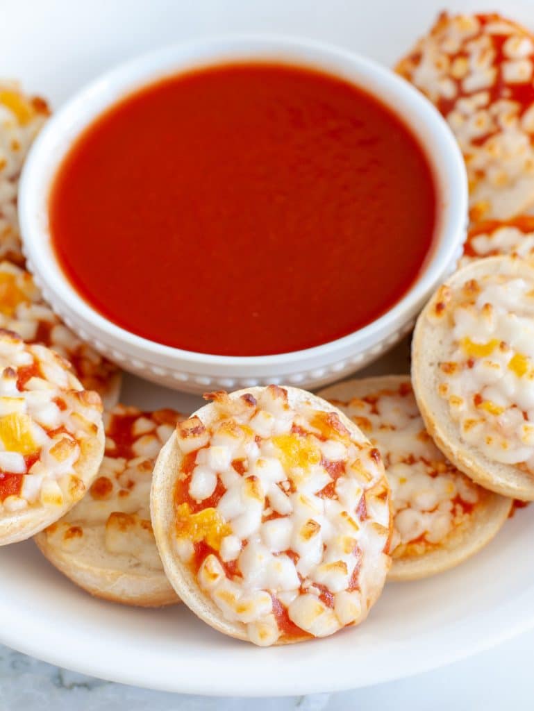 Plate of bagel bites on plate with bowl of red sauce. 