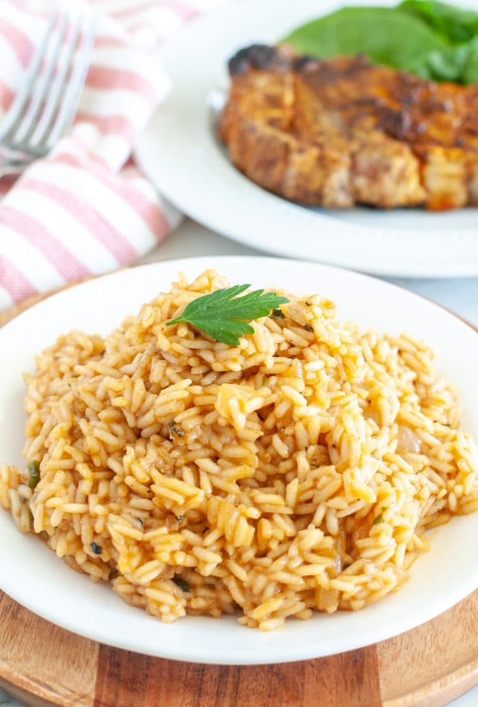 Plate of rice with steak in the background. 