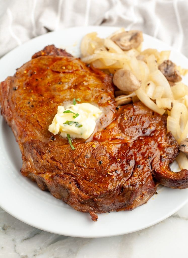 Steak on a plate topped with butter. 