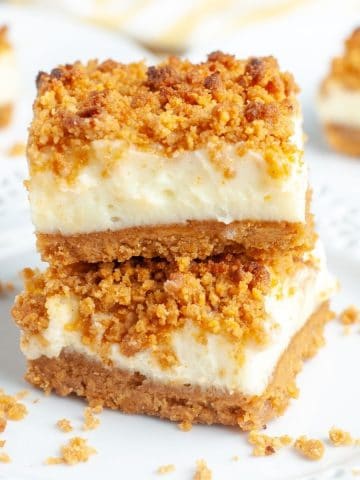 Dessert bars with crumb topping stacked on plate.