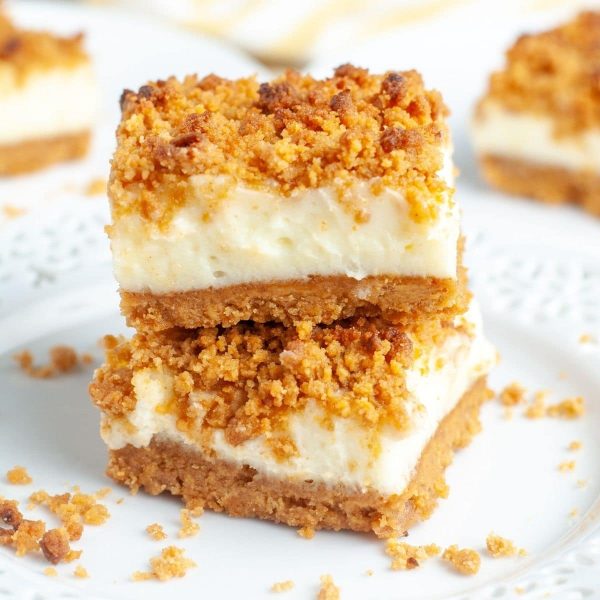 Dessert bars with crumb topping stacked on plate.