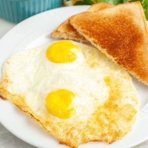 Cooked eggs on plate with toast.