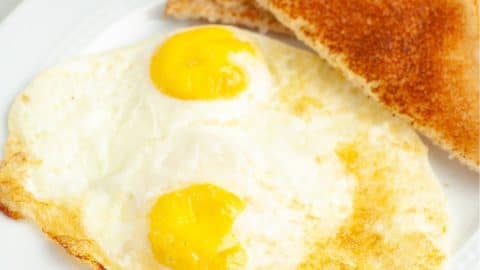 Cooked eggs on plate with toast.