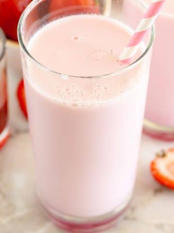 Two glasses of pink milk with strawberries.