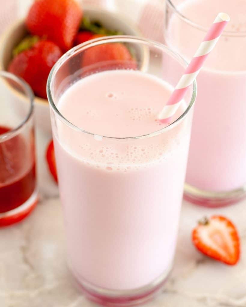 Glasses of milk with bowl of strawberries. 