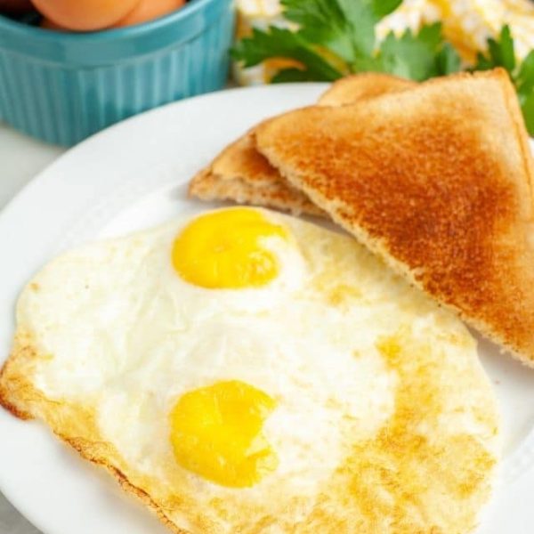 Fried eggs and toast on a plate.