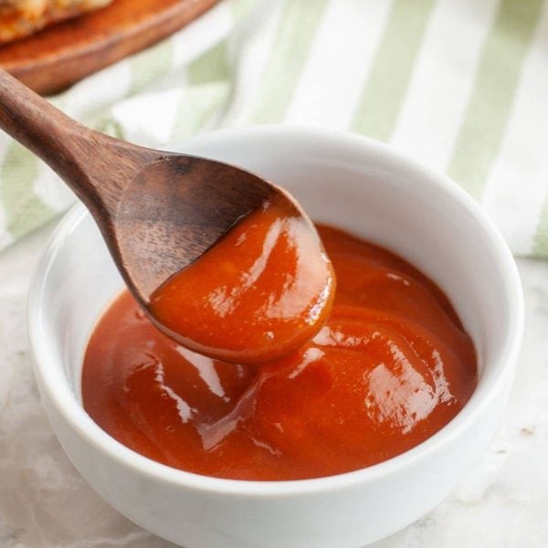 Bowl of red sauce and a wooden spoon.