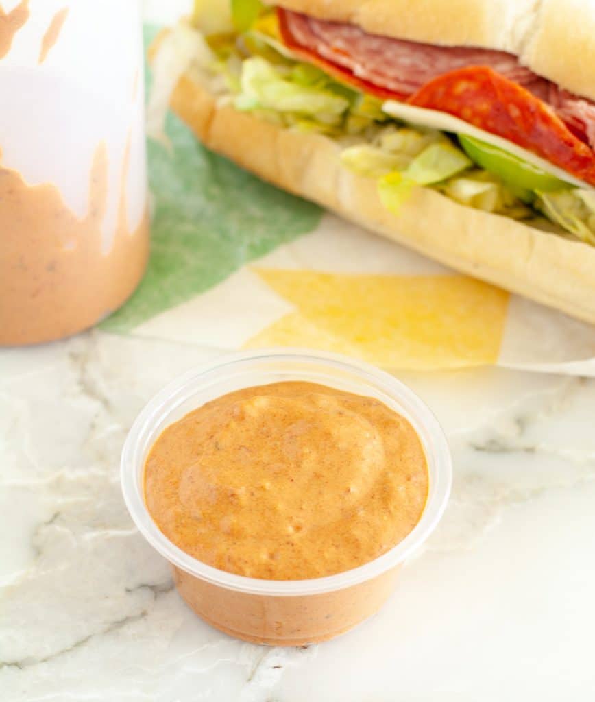 Cup of sauce and sandwich.