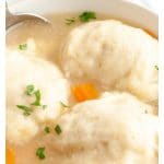 Dumplings on top of soup in a bowl.