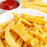Thick fries in a bowl with bowl of ketchup.