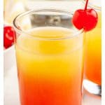 Shot glasses with juice and topped with a cherry.