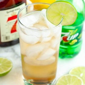 Glass filled with a drink and lime slice.