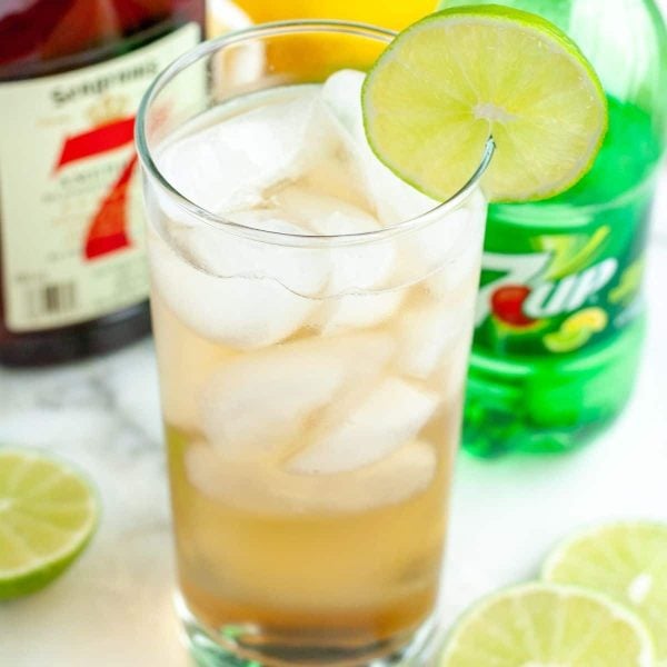 Glass filled with a drink and lime slice.