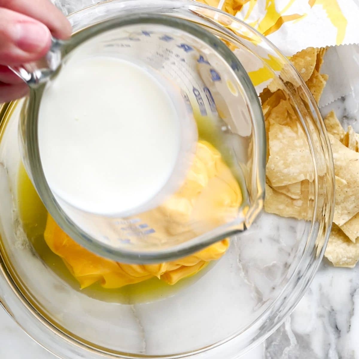 Milk pouring into a bowl of cheese sauce.