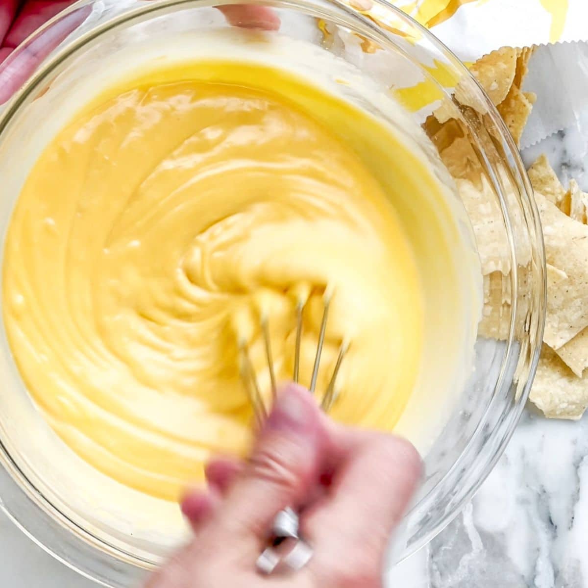 Bowl with cheese sauce and a whisk.