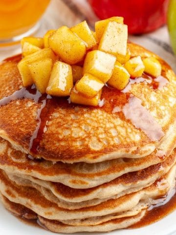 Stack of pancakes topped with apples.