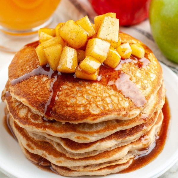 Stack of pancakes topped with apples.