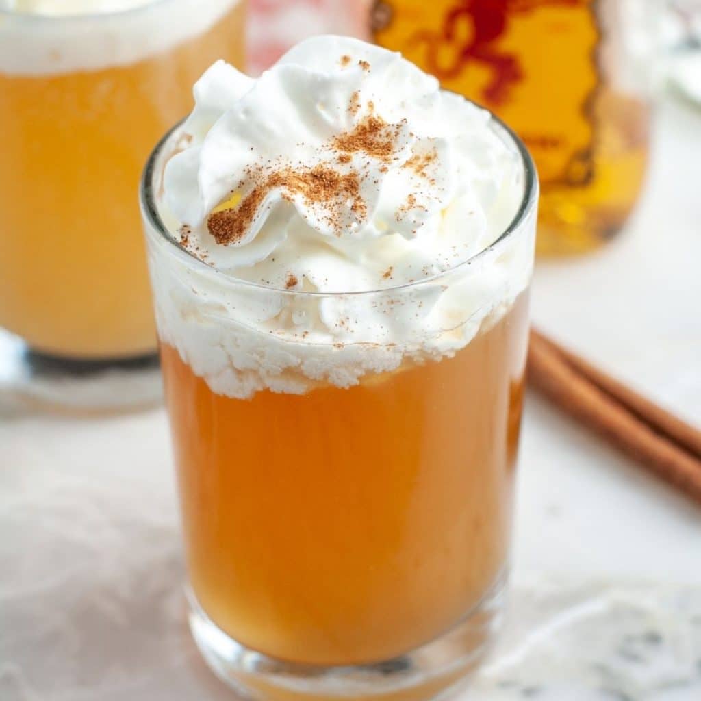Glass with apple juice topped with whipped cream.