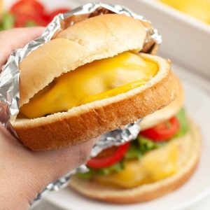 Hand holding cheeseburger.