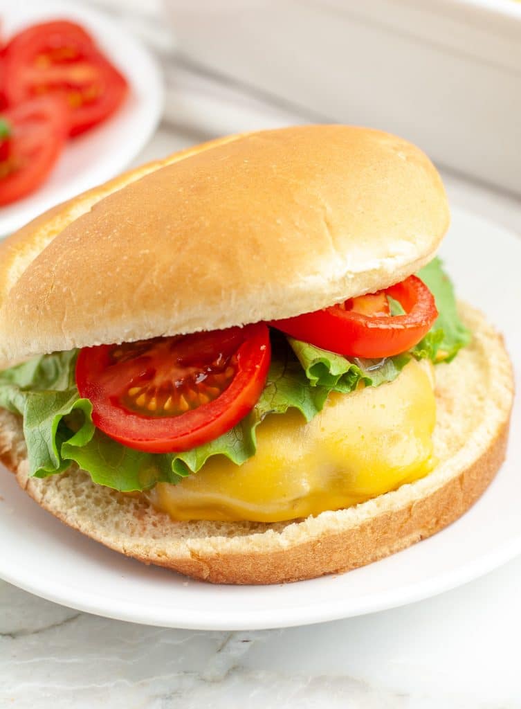 Cheeseburger on a bun with lettuce and tomato.