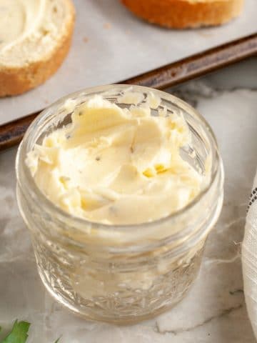 Butter in a jar with slices of toast.