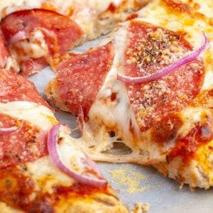Cooked pizza slice with onion and salami.