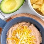 Bowl of beans, chips, and an avocado.
