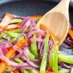 Skillet with veggies and wooden spoon.