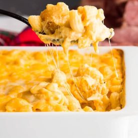 Baked Macaroni and Cheese in a square white casserole dish being spooned out