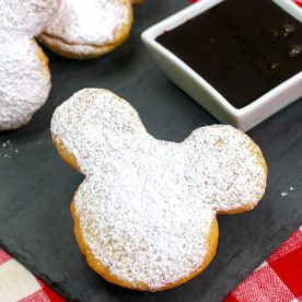 Mickey Mouse Shaped Beignets sitting on a square black plate