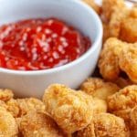 Fried chicken bites on a plate with bowl of ketchup.
