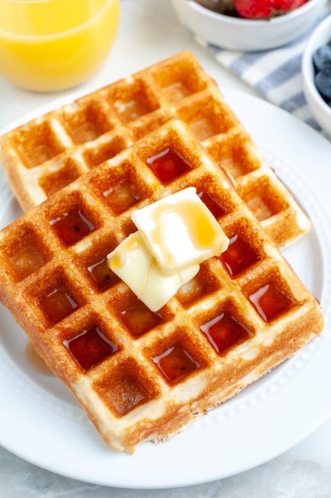 Plate of waffles with glass of orange juice.