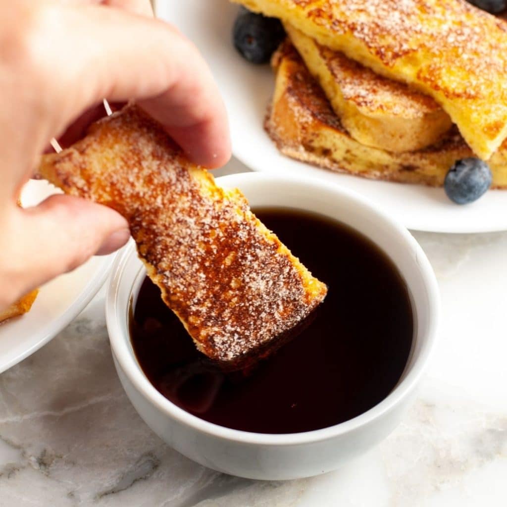 Hand holding french toast stick.