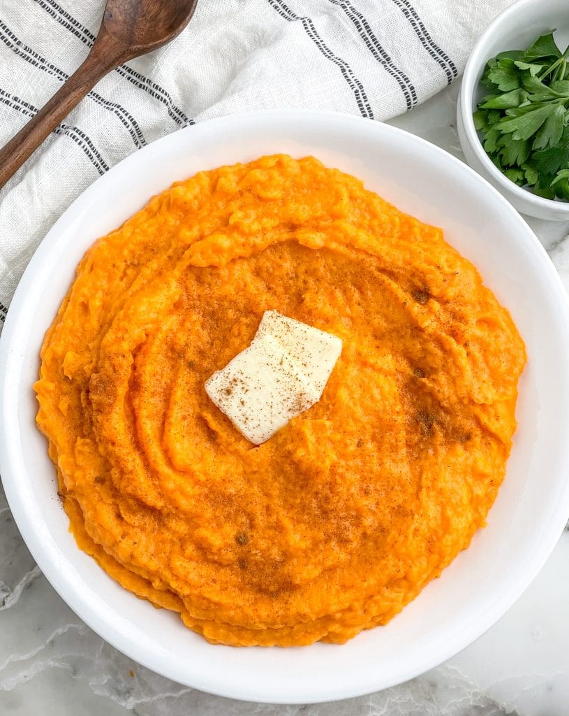 Sweet potatoes mashed in a bowl with butter.