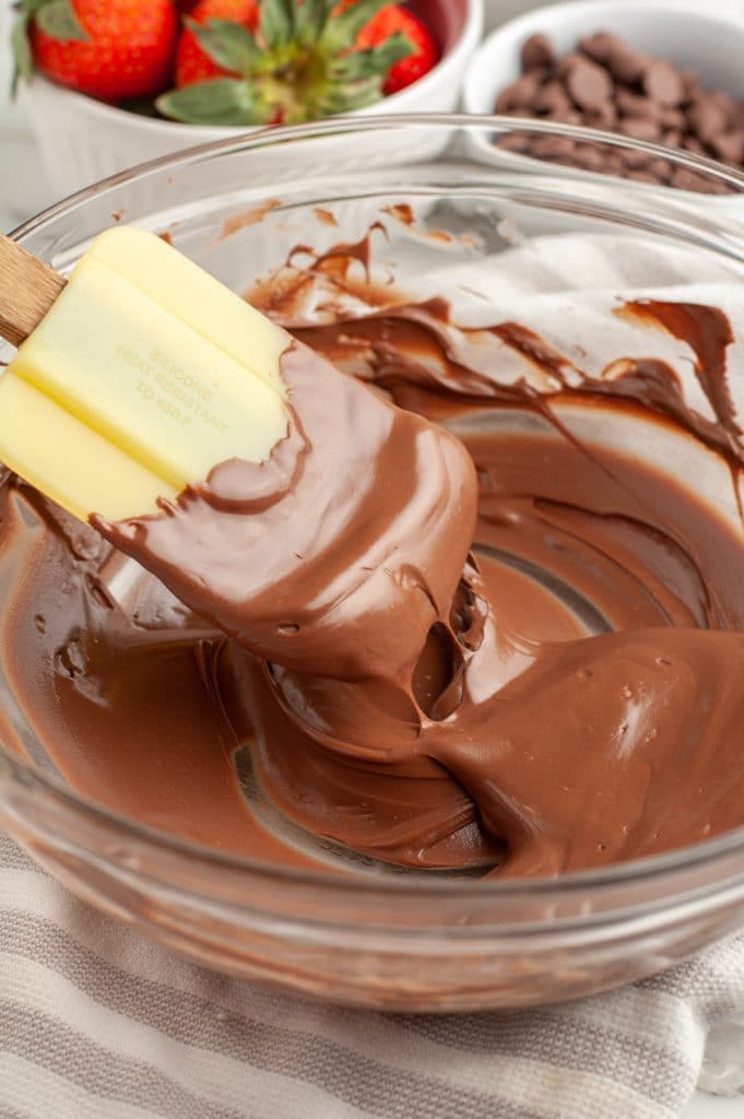 Bowl of melted chocolate and yellow spatula.