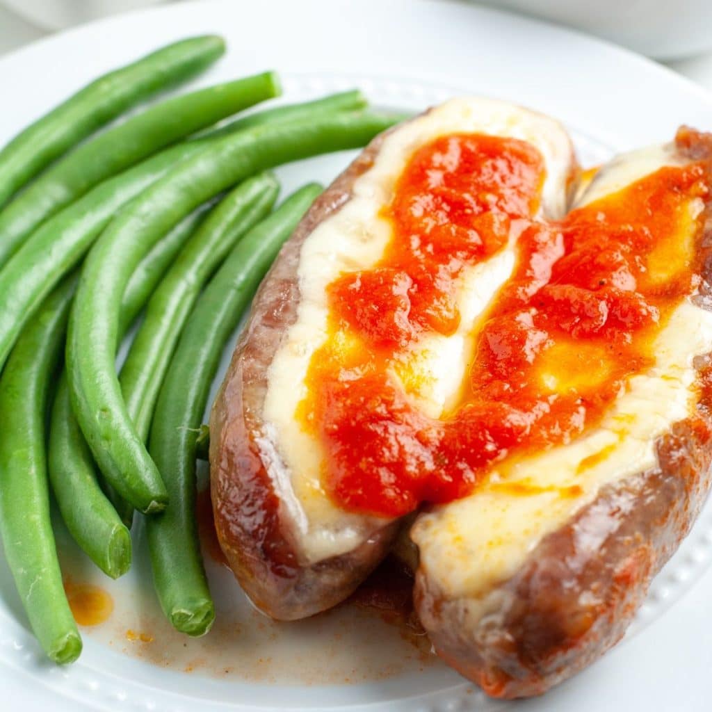 Plate of sausages and cheese with green beans.