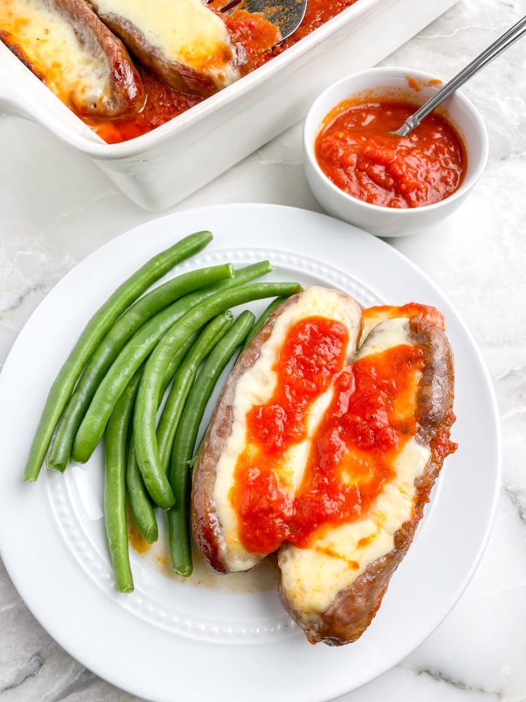 Plate with two sausages and green beans.