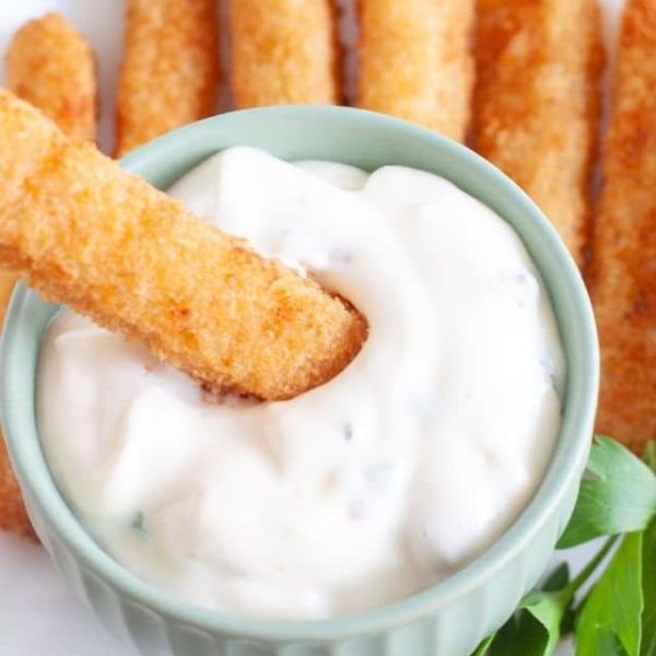 Bowl of sauce with fish stick.