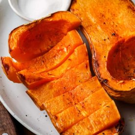 Whole roasted butternut squash on a plate.