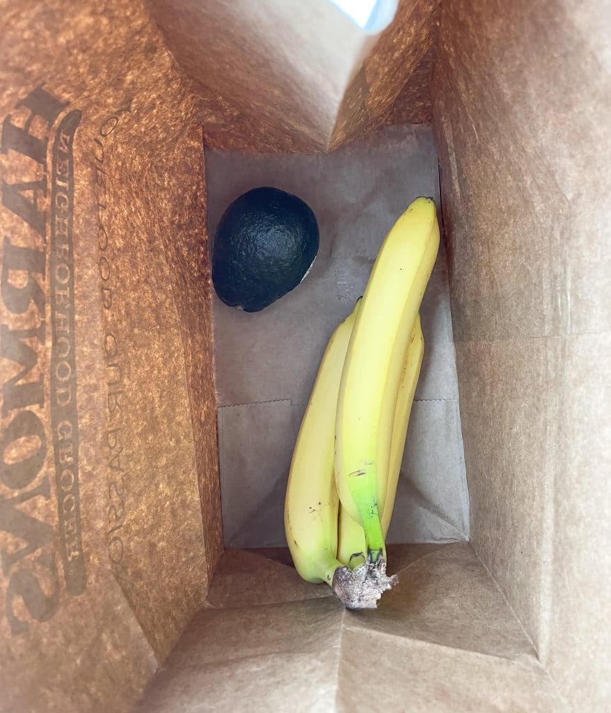 Bananas and avocado in a paper bag.
