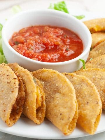 Plate of mini tacos with bowl of salsa.