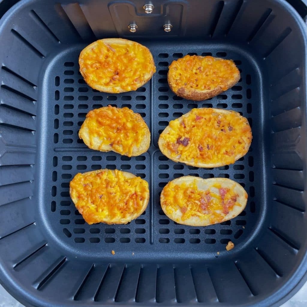 Cooked potato skins in air fryer basket.