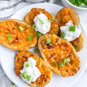 Plate of potato skins with cheese and sour cream.