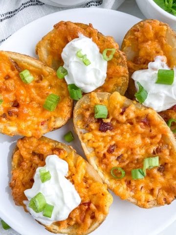Plate of potato skins with cheese and sour cream.
